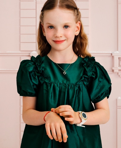 A girl in a green dress showing off her bracelets