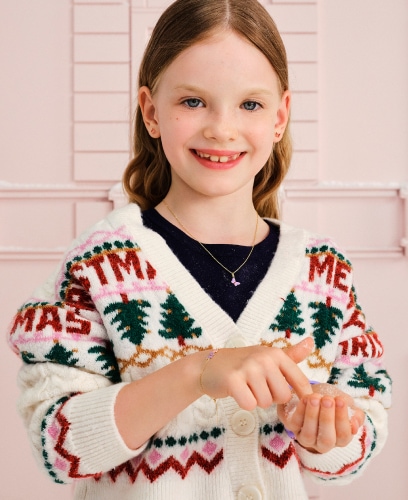 A girl in a Christmas sweater showing off her earrings.